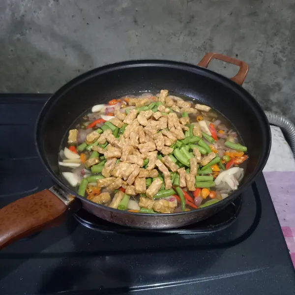 Masukkan air, tempe, dan buncis. Masak sampai buncis setengah matang.