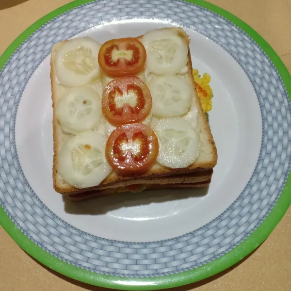 Tumpuk lagi dengan roti, beri mayonaise lalu potongan timun dan tomat, kemudian beri saus sambal, saus tomat dan mayonaise lali. Tutup dengan roti tawar kemudin mungkus.