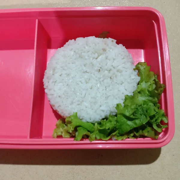 Siapkan wadah bekal masukkan nasi dan selada.