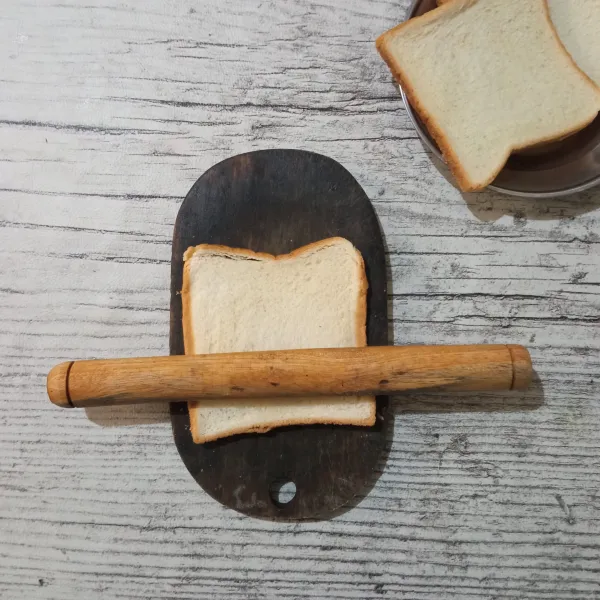 Letakkan roti tawar diatas talenan, lalu giling hingga pipih.