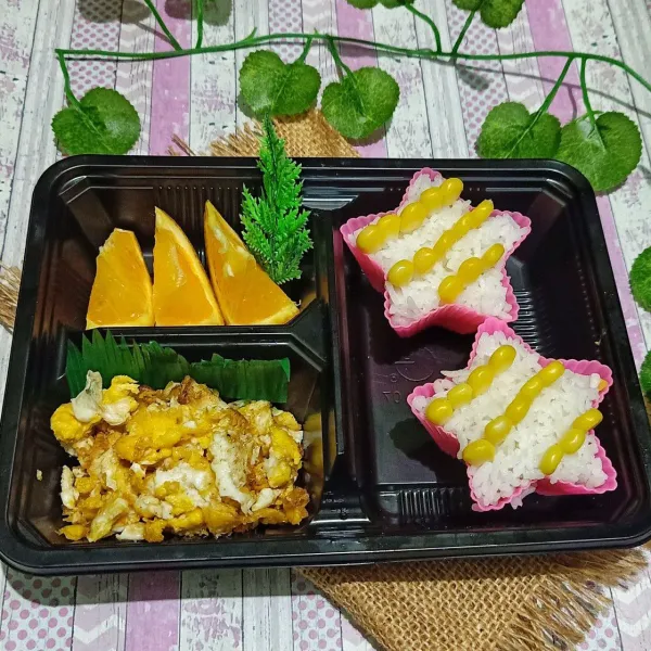 Nasi masukkan ke dalam cetakan bintang lalu tata jagung yang sudah direbus terlebih dahulu. Tata buah jeruk sunkist yang sudah dipotong dan tata scramble egg. Lalu siap disajikan untuk bekal.