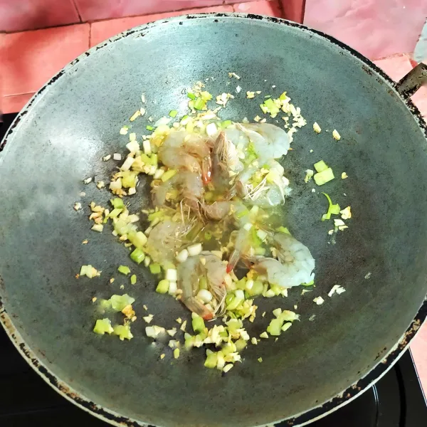 Tumis bawang putih cincang hingga harum, masukkan daun bawang, lalu masukkan udang. Masak hingga udang berubah warna.