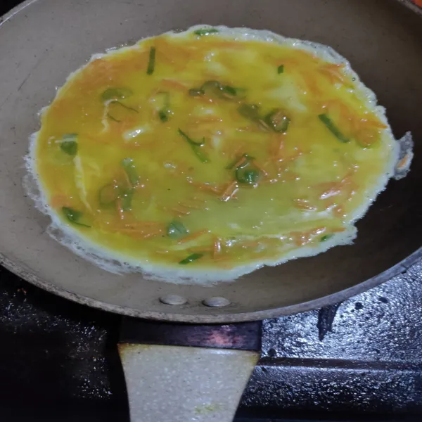 Masukkan setengah adonan telur ratakan, biarkan setengah kering lalu gulung sisihkan pada pinggir pan.