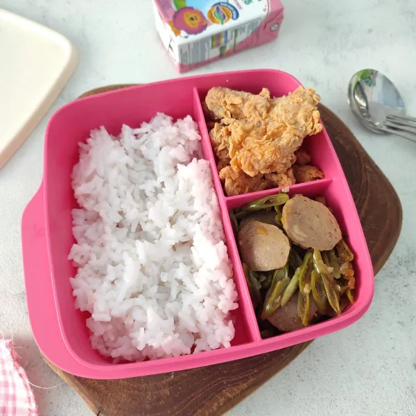 Tata tumis buncis bakso dalam kotak bekal. Sajikan bersama nasi dan lauk kesukaan anak.