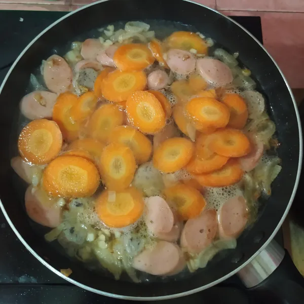 Masukkan sosis dan bakso.
Tuang air, masukkan wortel.