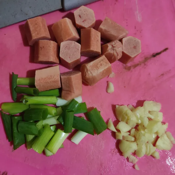 Potong-potong sosis dan daun bawang, cincang bawang putih.
