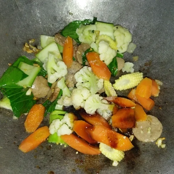 Tambahkan wortel, kembang kol dan jagung putren yang tadi sudah direbus, beri garam, lada bubuk, saus tiram dan kecap manis, aduk rata lalu cicipi.