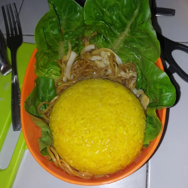 Susun bento. Dimulai dari selada, kemudian masukkan yakisoba. Cetak nasi kuning di mangkuk bulat. Letakkan.