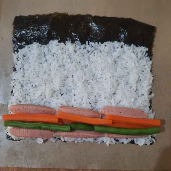 Susun isian gimbap di atas nasi secara memanjang.