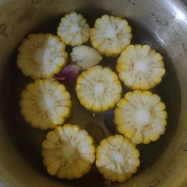 Didihkan air bersama bawang merah dan bawang putih geprek, masukkan jagung. Masak hingga jagung empuk.