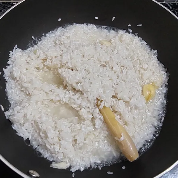 Masukan beras yang sudah dicuci bersih, tambahkan sedikit air, aduk rata. Matikan api.