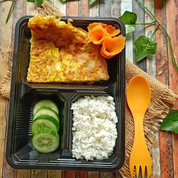 Sajikan di lunch box anak berisikan nasi, irisan mentimun, wortel dibentuk bunga dan mie dog. Lalu siap disajikan untuk bekal anak.