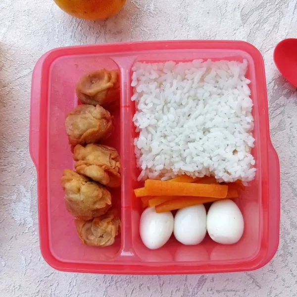 Tata bakso krispy dalam kotak bekal bersama nasi, wortel rebus dan telur puyuh rebus.