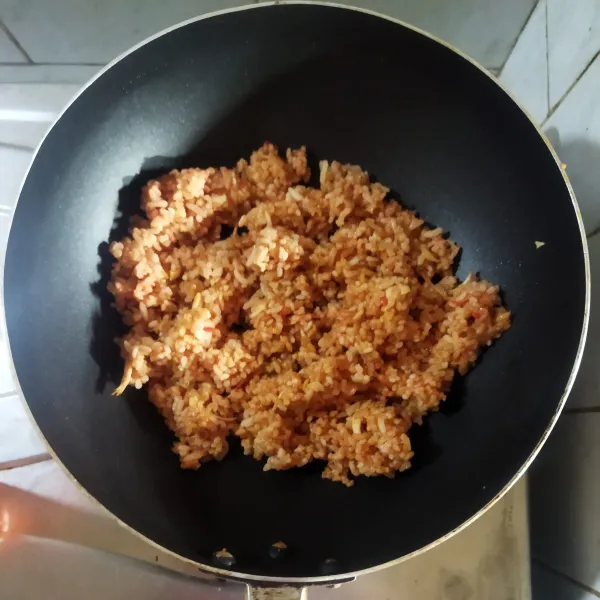 Aduk dan masak hingga matang dan nasinya berwarna kemerahan. Angkat. Sajikan nasi goreng diatas piring lalu tambahkan telur rebus, ayam suwir, irisan timun dan tomat.