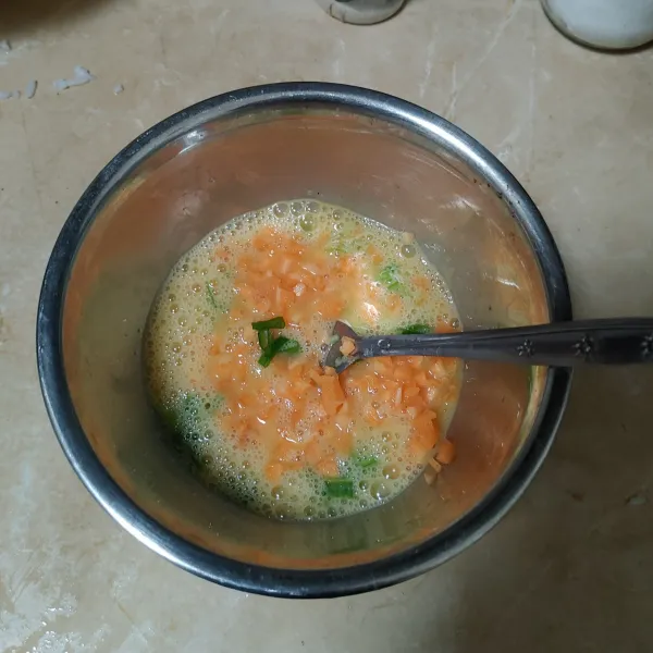 Masukan wortel dan daun bawang kedalam kocokan telur, lalu kocok hingga tercampur rata.