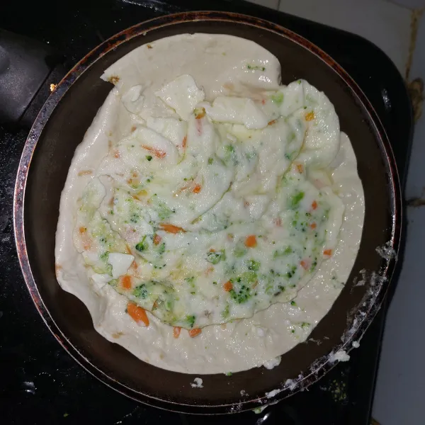 Tuangkan dulu campuran putih telur. Setelah setengah matang tambahkan tortilla, agak tekan agar menempel. Lalu balik.