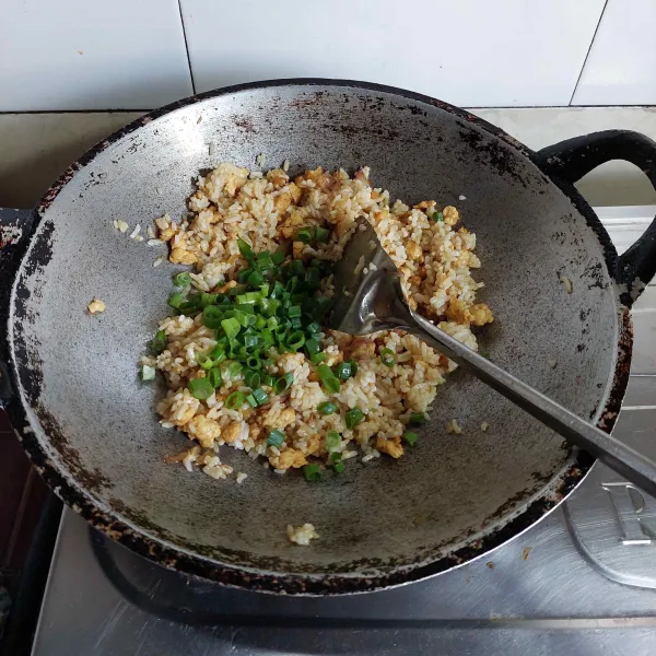 Masak hingga bumbu meresap dan nasi agak mengering, tambahkan daun bawang, koreksi rasa.