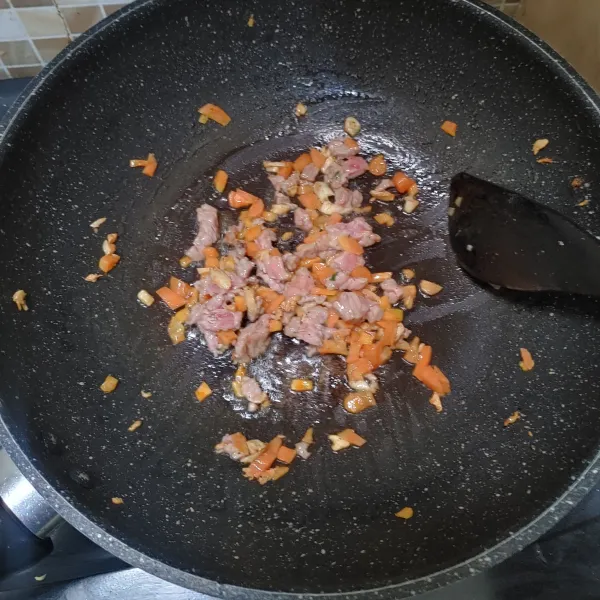 Tumis bawang putih hingga harum, lalu masukan daging sapi cincang dan wortel. Masak hingga daging berubah warna.