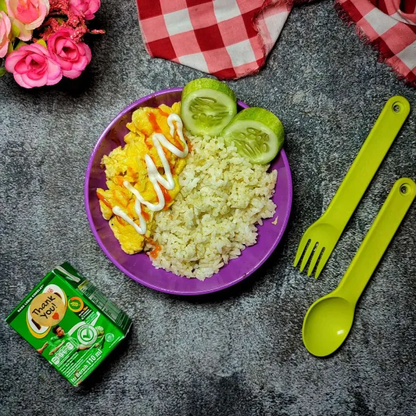 Sajikan nasi butter ke dalam lunch box, lalu beri scramble egg. Beri sedikit saus tomat dan mayonnaise. Lengkapi dengan susu cair sebagai menu bekal anak.