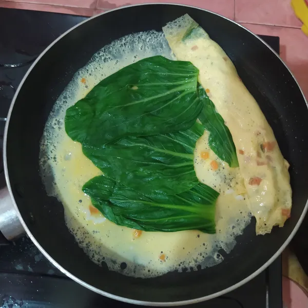 Gulung, sisakan sedikit bagian ujungnya lalu pinggirkan.
Tuang ⅓ bagian lagi, beri pokcoy, gulung, pinggirkan.