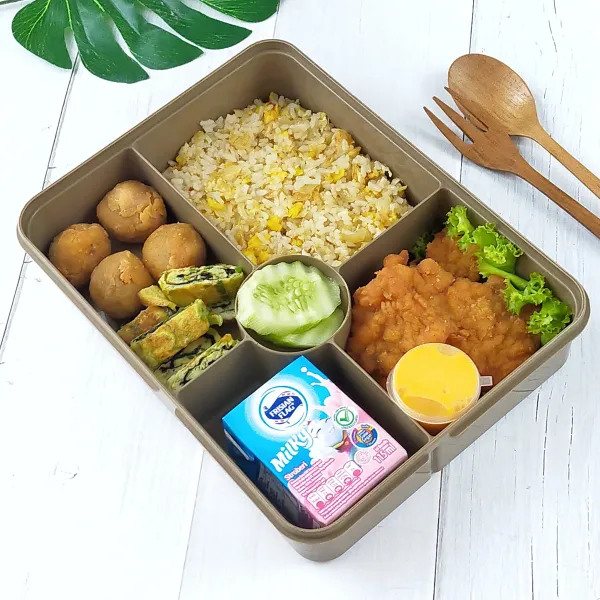 Penyajian: siapkan wadah bekal, masukkan nasi goreng saus tiram, lalu beri bahan pelengkap bakso goreng crispy, dadar telur Nori, ayam crispy, timun, saus keju dan Frisian flag milky strawberry.