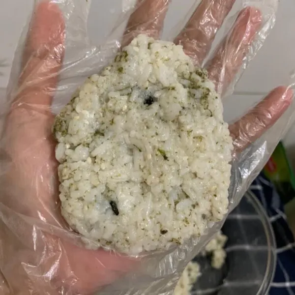 Ambil sebagian nasi untuk dibentuk menjadi onigiri sesuai selera. Pipihkan terlebih dahulu nasi.