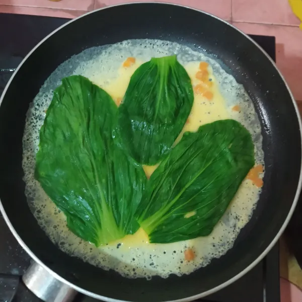 Panaskan fry pan anti lengket lalu olesi minyak. Tuang ⅓ bagian telur, tata daun pokcoy di atasnya.