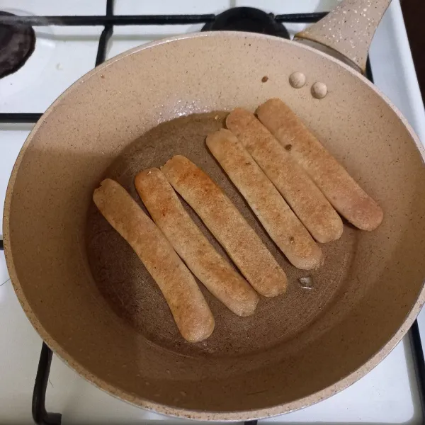 Belah sosis menjadi 2 bagian, kemudian panggang dengan sedikit minyak goreng hingga berubah warna, sisihkan.