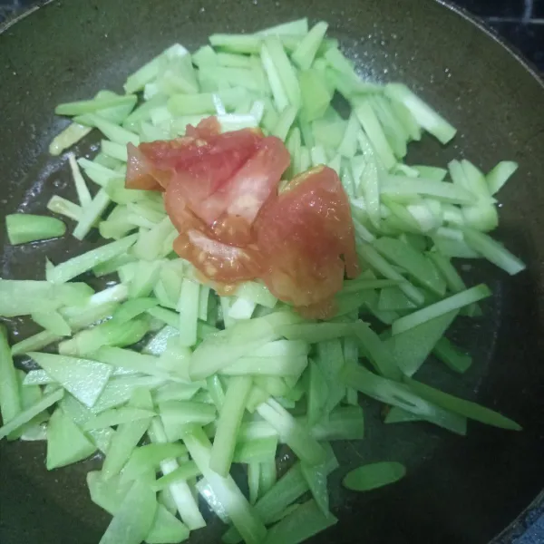 Masukkan irisan tomat ke dalam wajan.