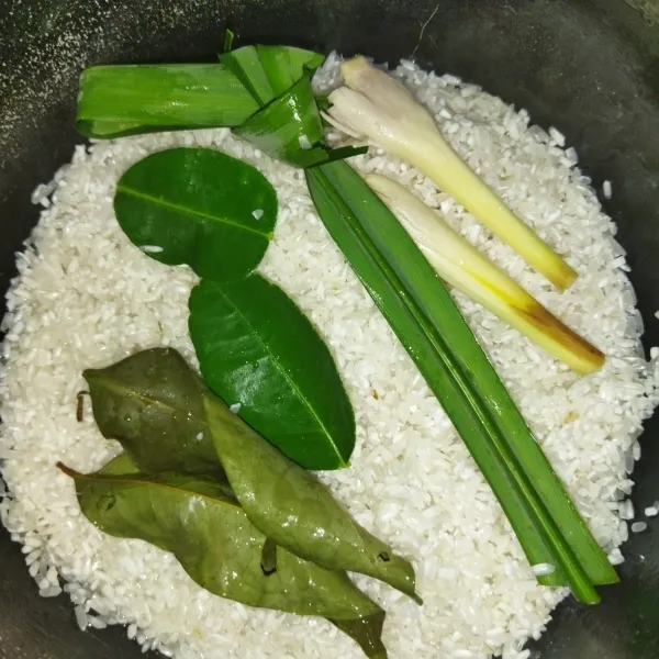 Siapkan beras yang sudah dicuci, tambahkan daun salam, serai, daun jeruk dan daun pandan.