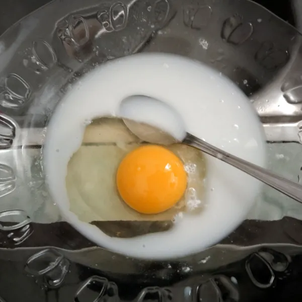 Kocok rata susu dan telur dalam piring.