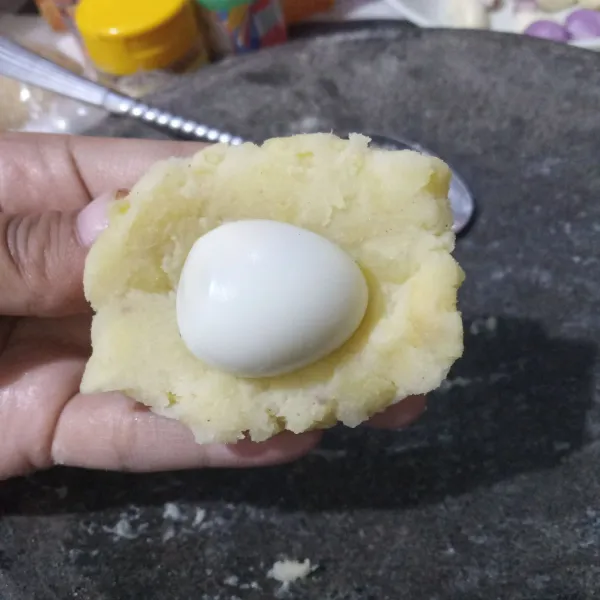 Ambil secukupnya adonan dan pipihkan, lalu beri telur puyuh serta bulatkan.