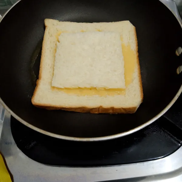 Tutup tengah roti dengan roti yang di potong tadi, kemudian panggang di sisi lainnya. Setelah matang, lalu sajikan.