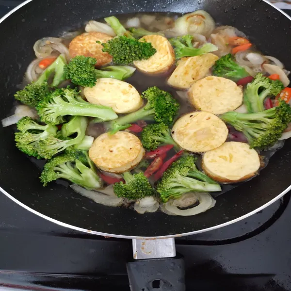 Masukkan brokoli, lalu tumis sebentar, kemudian tuangkan air, tofu, garam, kaldu jamur dan saus tiram.
