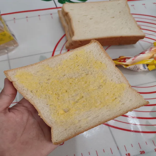 Ambil selembar roti tawar, oleskan margarin ke seluruh permukaan roti.