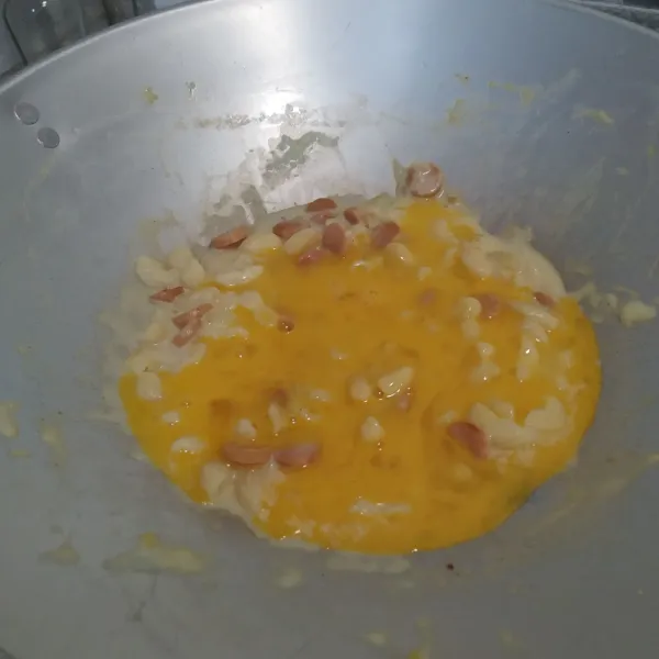Setelah adonan hangat, masukkan telur kocok, lalu aduk lagi hingga tercampur rata.