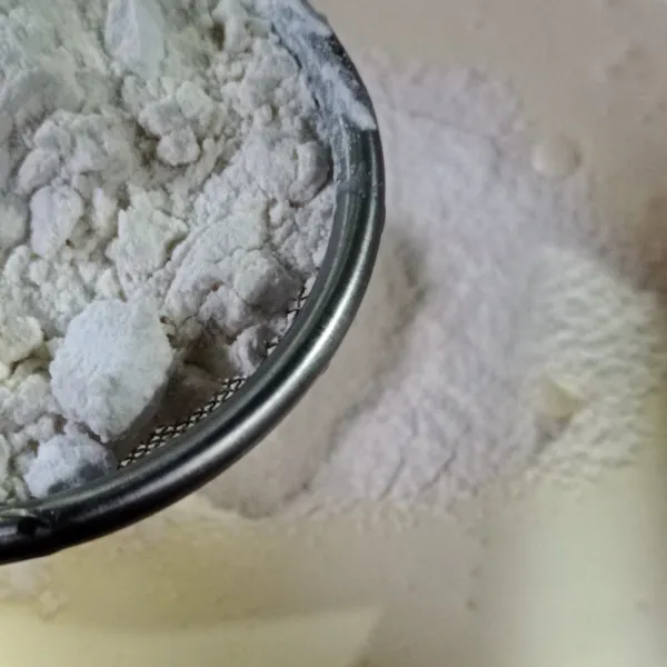 Masukkan tepung terigu serta tepung tapioka sedikit demi sedikit sambil diayak, aduk kembali dengan mixer kecepatan rendah hingga rata.