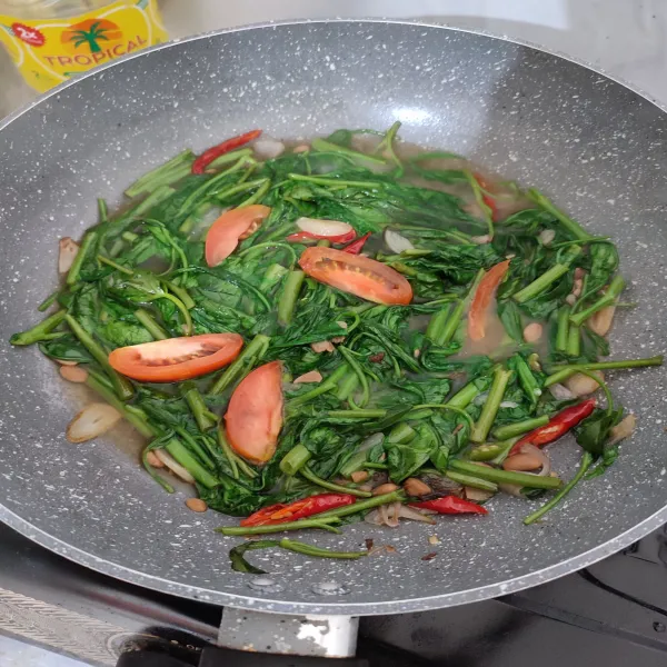 Masukan kangkung, masak hingga kangkung setengah mateng, lalu tambahkan tomat Iris. Aduk merata dan masak hingga kangkung mateng.