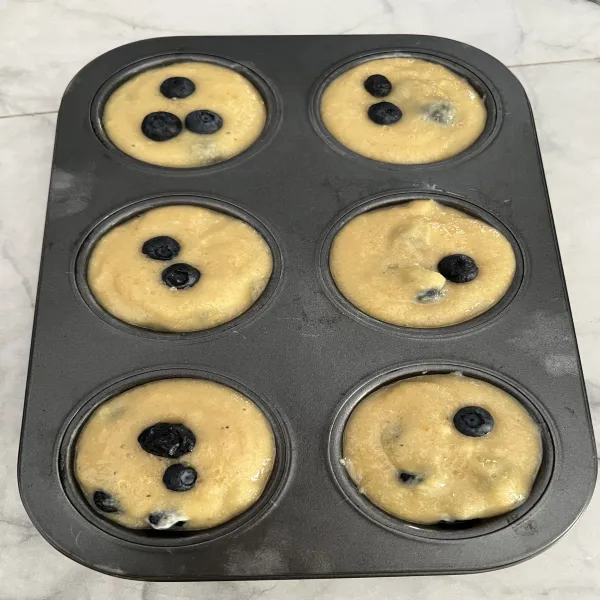 Siapkan loyang muffin yang sudah diberi kertas cup (aku tidak memakai, jadi aku oles loyang dengan minyak sedikit). 
Lalu beri 2 sendok adonan dan beri topping blueberry.