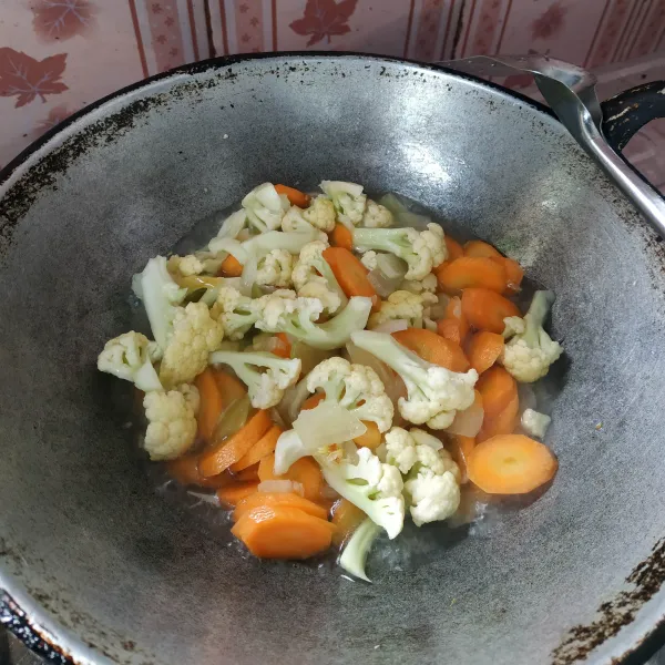 Setelah bumbu matang, tambahkan air secukupnya lalu masukkan wortel dan bunga kol masak hingga setengah matang.