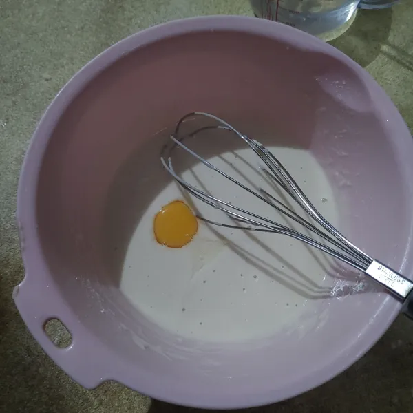 Tambahkan tepung, garam dan tuang air sedikit demi sedikit, aduk hingga merata. Kemudian tambahkan kuning telur, aduk rata kembali.