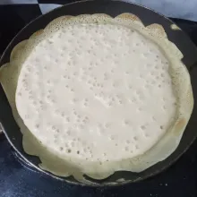 Panaskan teflon dengan api kecil tanpa dioles apapun. Tuang adonan lalu buat pinggiran, biarkan hingga muncul gelembung banyak dan merata.
