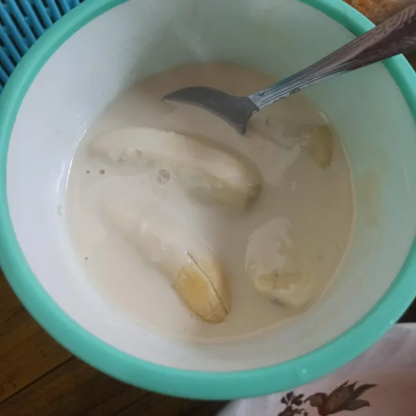 Kupas pisang, kemudian celupkan ke dalam adonan basah.
