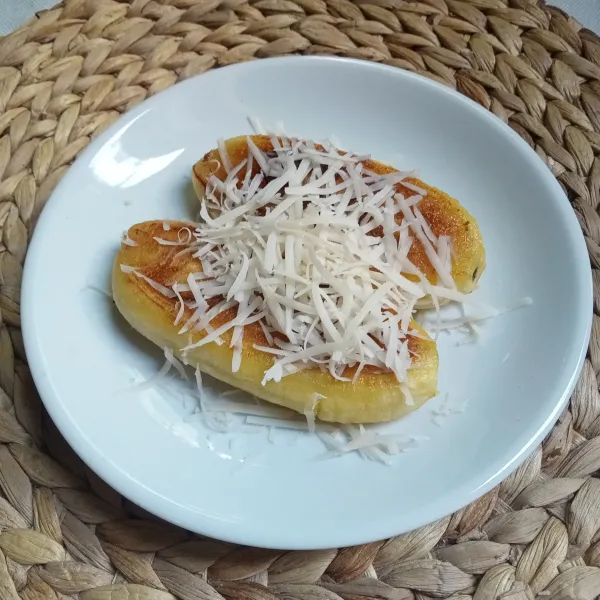 Tata pisang di piring, beri susu kental manis dan taburi dengan keju parut.