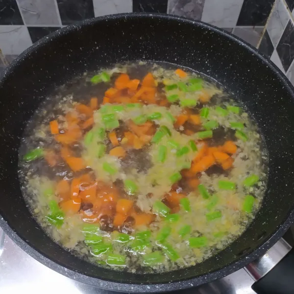 Masukkan wortel dan buncis, lalu tumis sebentar sampai layu. Kemudian masukkan air dan masak sampai mendidih.