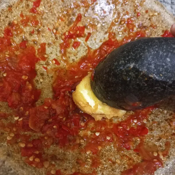 Ambil telur rebus goreng, penyet di atas sambal.