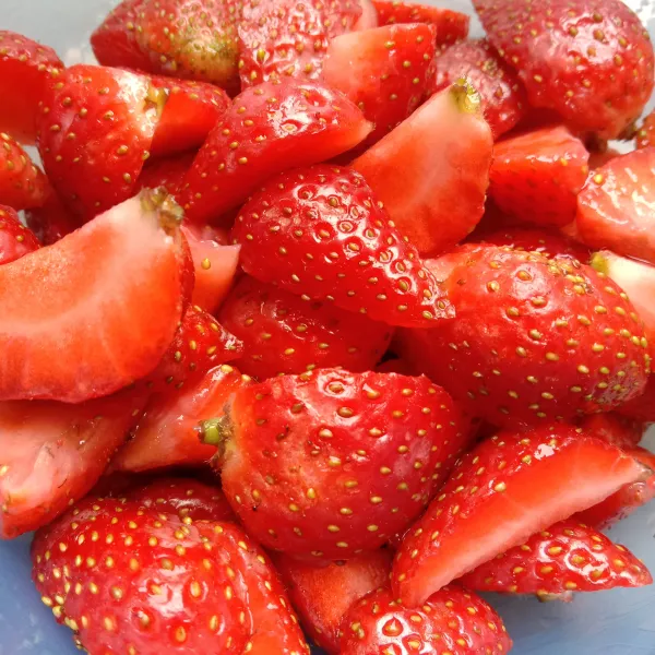 Cuci bersih buah strawberry, buang daunnya, dan potong menjadi bagian yang lebih kecil.