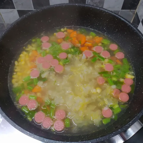 Masukkan jagung, jamur es, dan irisan sosis. Bumbui dengan kaldu jamur dan garam, lalu aduk rata sambil cicipi rasa sesuai selera. Masak sampai sayur matang, kemudian angkat dan sajikan.