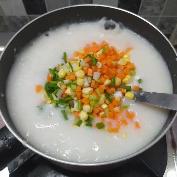 Jika bubur sudah meletup-letup masukkan sayuran wortel, jagung dan daun bawang. Masak sampai sayuran matang.