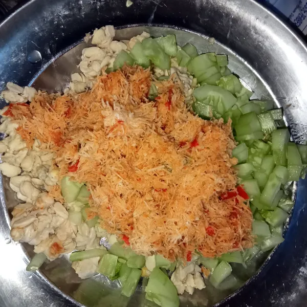 Dalam wadah hancurkan tempe yang sudah direbus tadi, cacah mentimun dan masukkan kelapa berbumbu trancam.